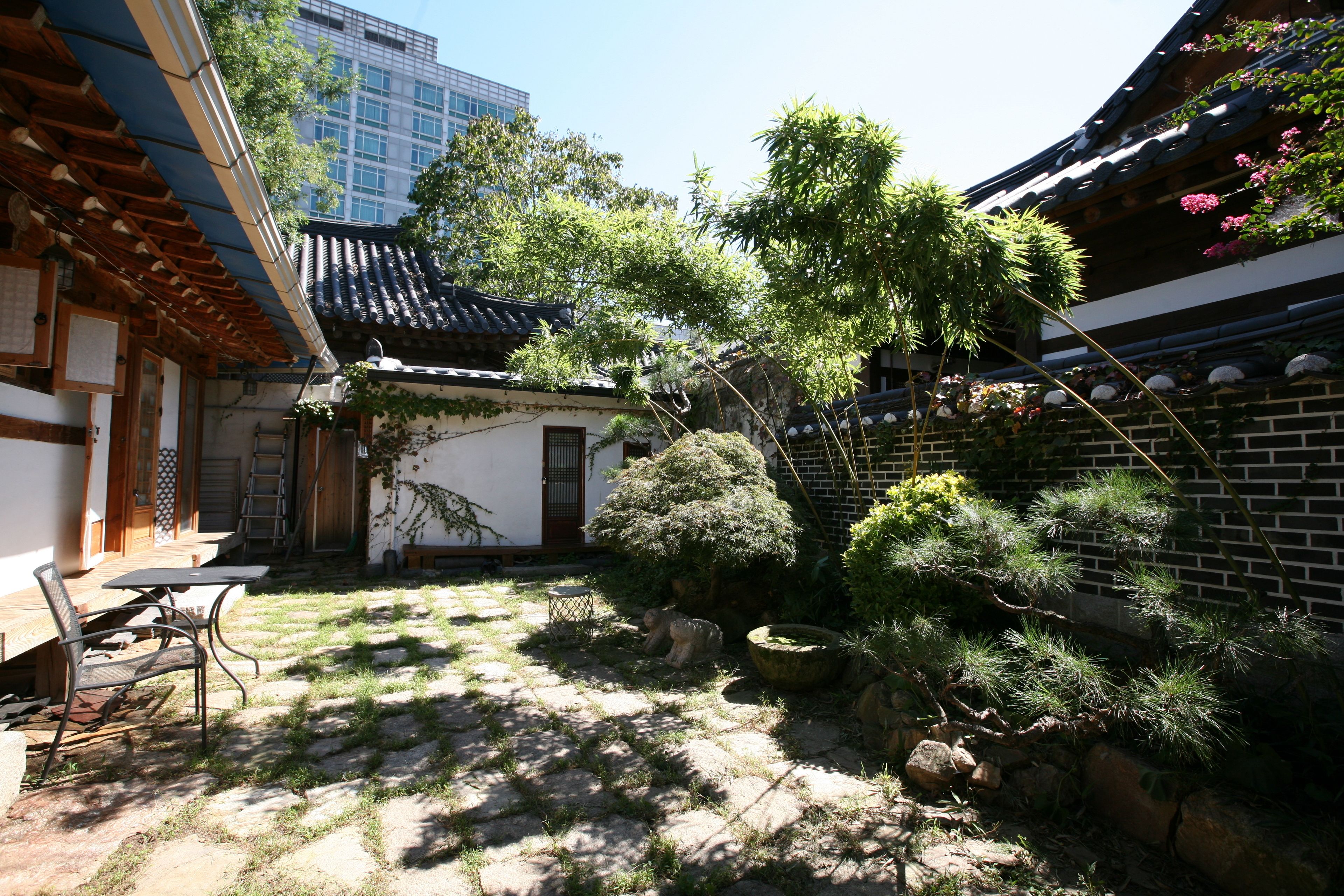 Un jardín japonés tradicional con senderos de piedra, una pequeña mesa de madera y un farol de piedra.