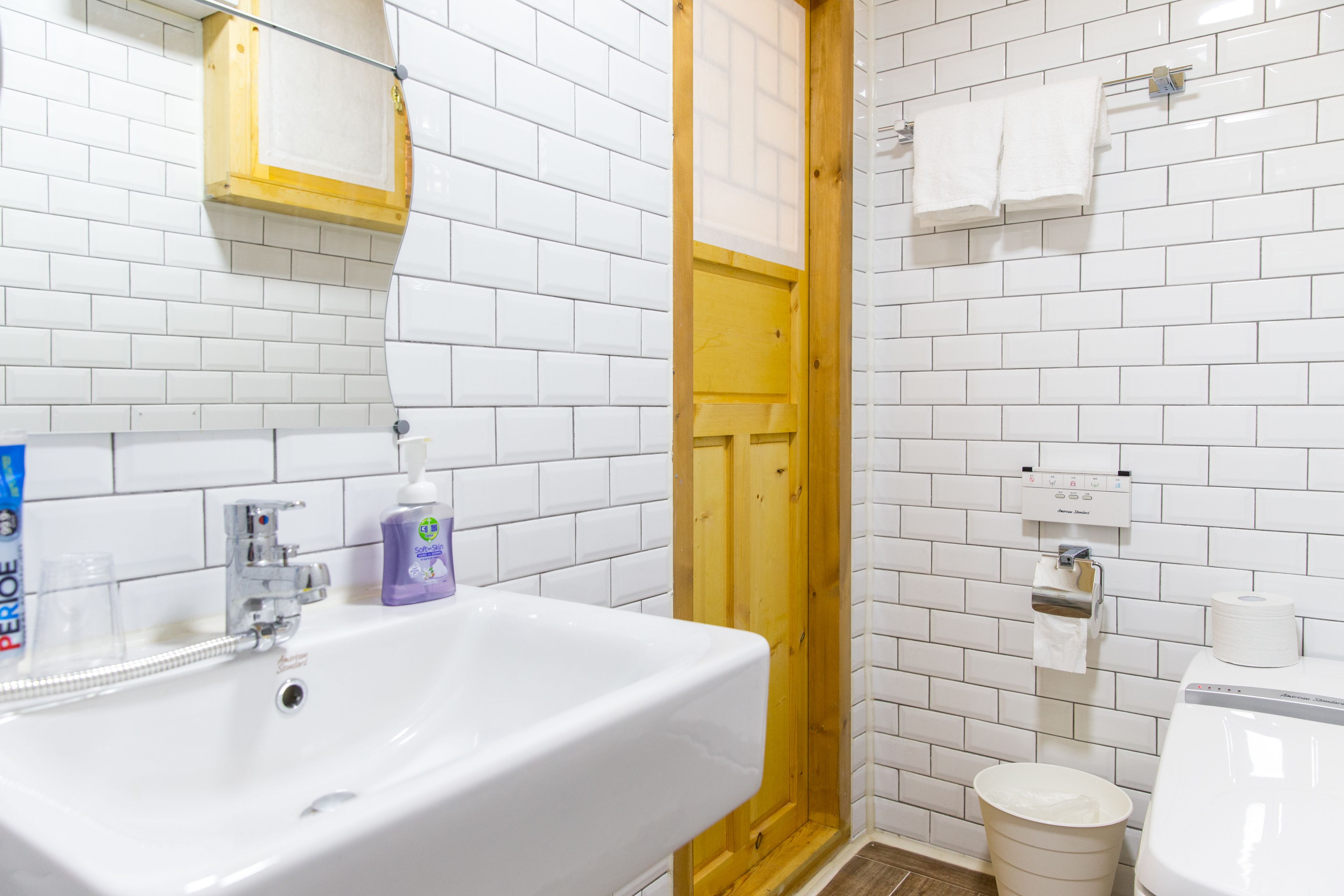 A bathroom with a white sink, mirror, and wooden door.