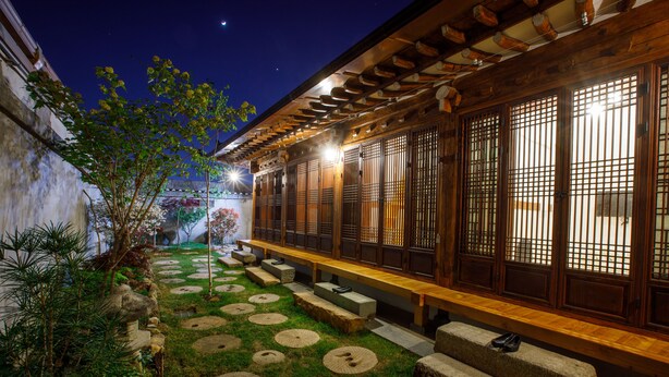 A traditional Japanese-style building with tatami mat flooring and a wooden bench along the side. - Gaeunchae (Jeonju)