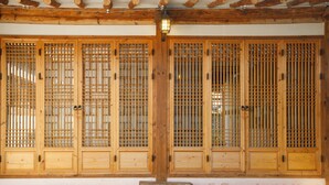 A traditional wooden building with large wooden doors and a bench in front. - Gaeunchae (Jeonju)
