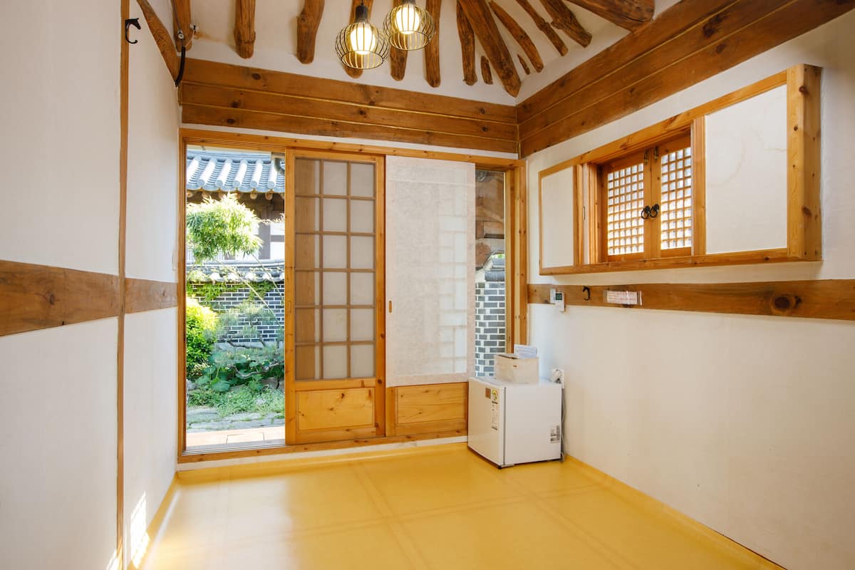 A traditional Japanese room with wooden beams, a sliding door, and a small refrigerator.