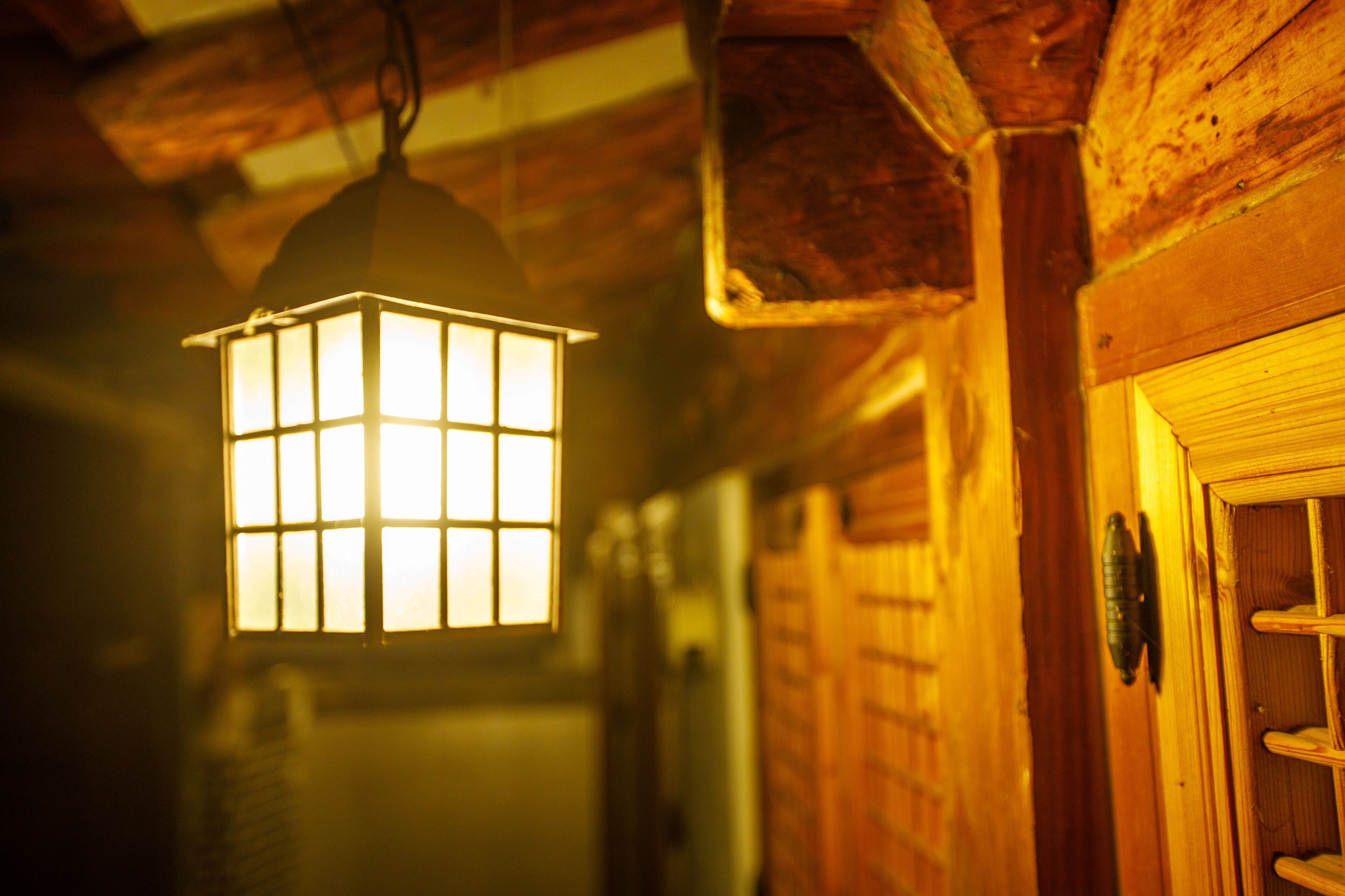A wooden interior with a hanging lantern and a door.