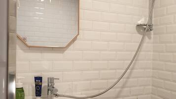 Een badkamer met een witte wastafel, een spiegel en een douche.