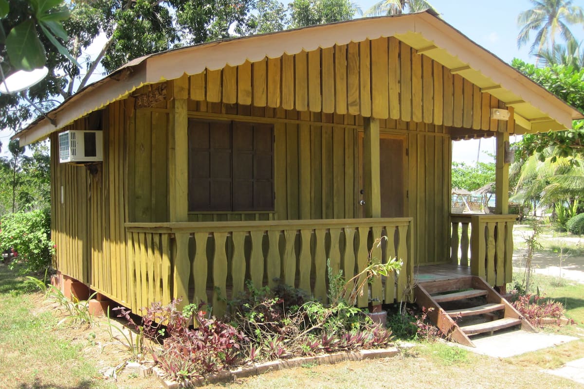 Una pequeña construcción de madera con un porche, una ventana y una puerta.