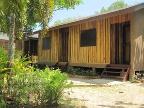 A wooden cabin with two windows, a porch, and a small garden area.