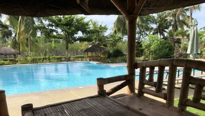 Eine Holzterrasse mit einem Pool im Hintergrund.