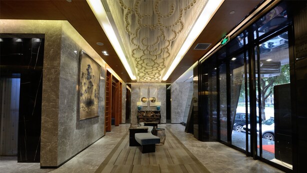 Un vestíbulo con piso de mármol, zona de estar central y techo decorativo.
