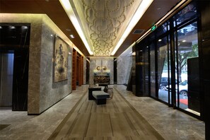 Un vestíbulo con piso de mármol, zona de estar central y techo decorativo.