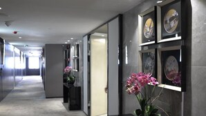 Un pasillo moderno con piso alfombrado, obras de arte enmarcadas en las paredes y una orquídea en maceta.