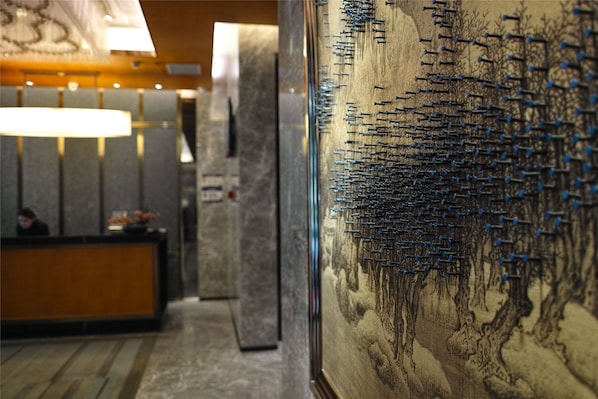 Un espace d’accueil agrémenté d’un mur en marbre et d’une grande œuvre d’art aux détails soignés.