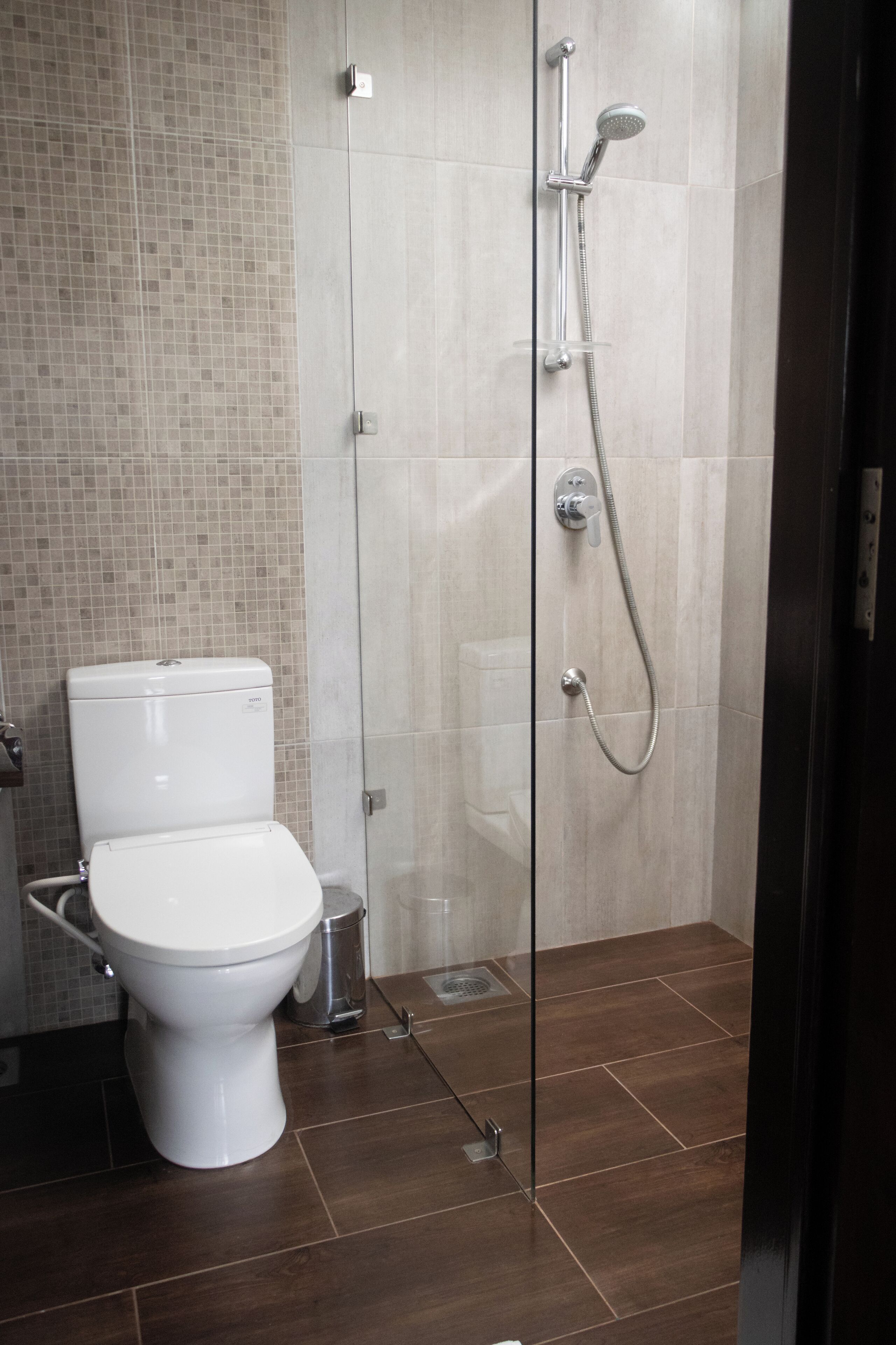 Un baño moderno con ducha de vidrio, inodoro blanco y suelo de baldosas.