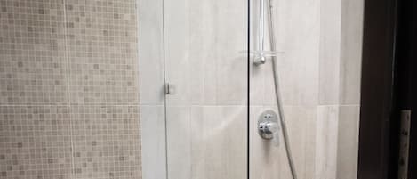 A modern bathroom with a glass-enclosed shower, a white toilet, and a tiled floor.