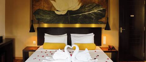 Una habitación de hotel con una cama, una gran obra de arte floral en la pared, suelo de madera y una puerta con un número.