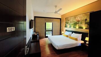 A modern hotel room with a large bed, a ceiling fan, a painting of lotus flowers, and a number sign on the door.