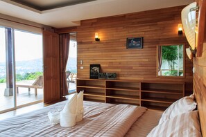 A bedroom with a large bed, wooden wall paneling, and a view of the outdoors.