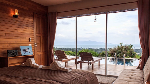 A bedroom with a large bed, a sofa, and a view of a pool and mountains.