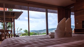 A bedroom with a large bed, a view of the mountains, and a wooden balcony.