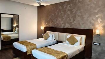 A hotel room with two beds, a ceiling fan, a large mirror, and a geometric-patterned wall.