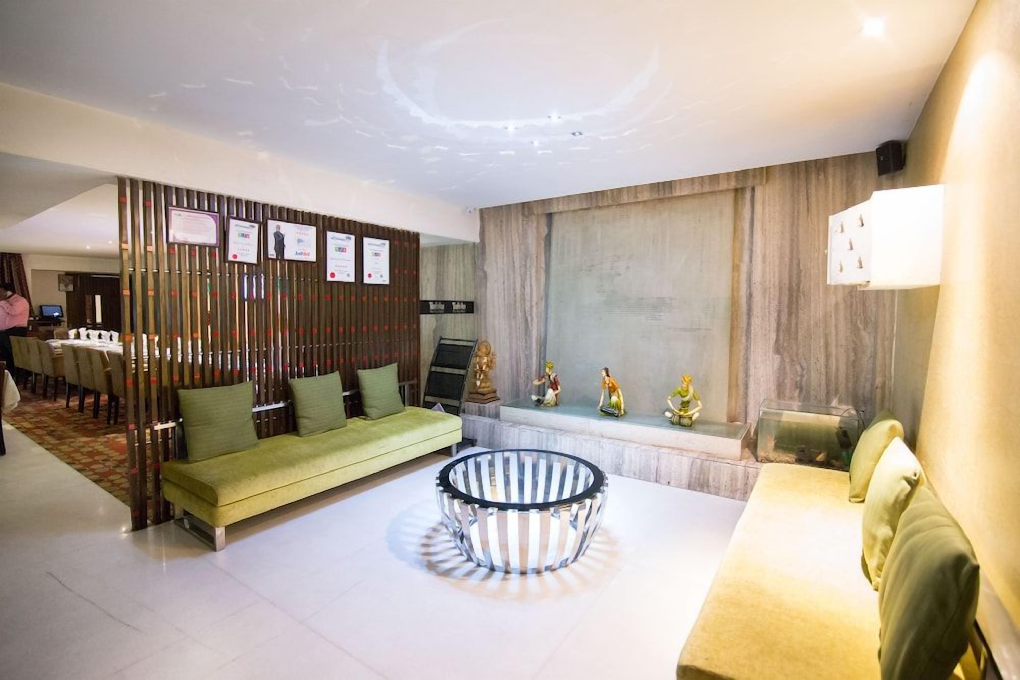 A modern living room with a green sofa, a round coffee table, and a decorative wall with plaques.