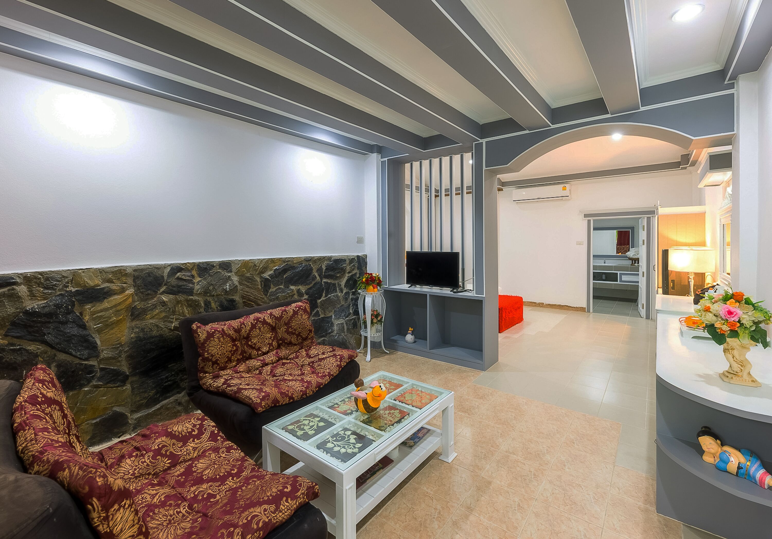 A modern living room with a stone accent wall, a sofa set, a coffee table, and a TV.