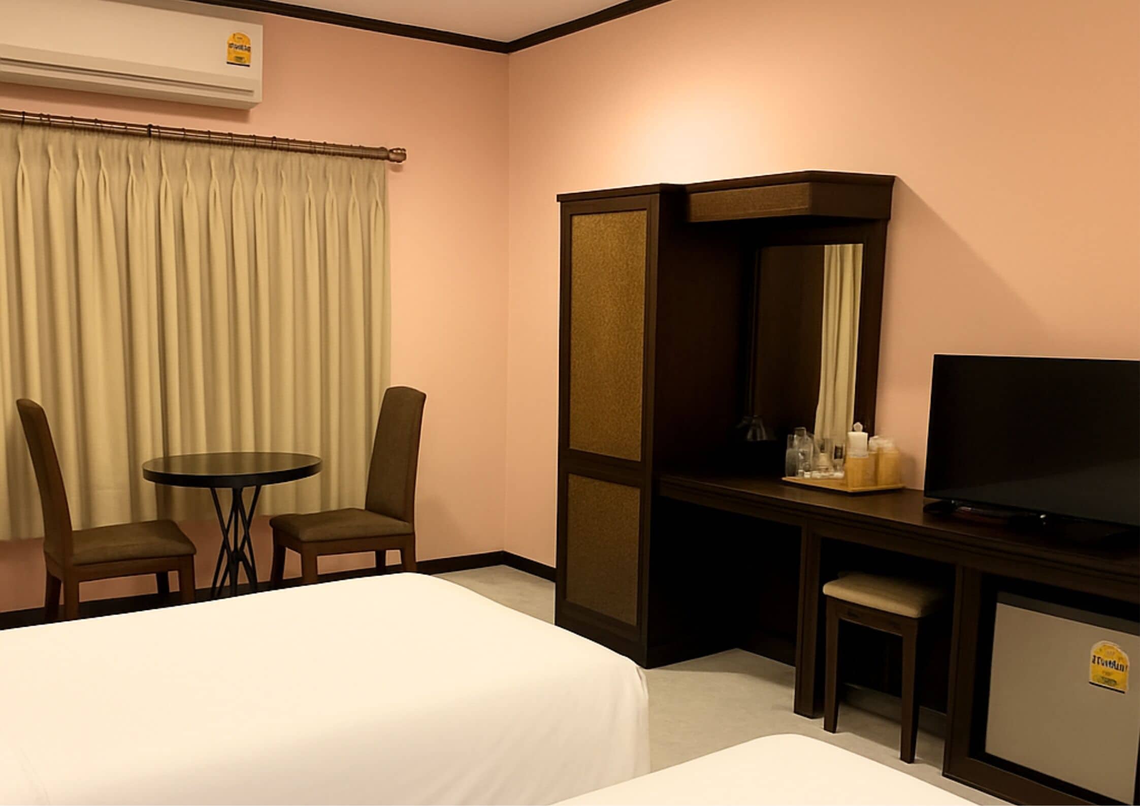 A hotel room with a bed, a desk with a chair, a television, and a minibar.