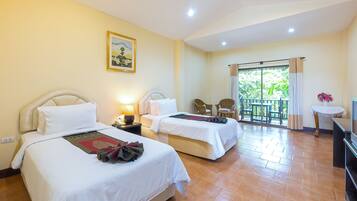Habitación de hotel con dos camas, un balcón con sillas y una televisión.