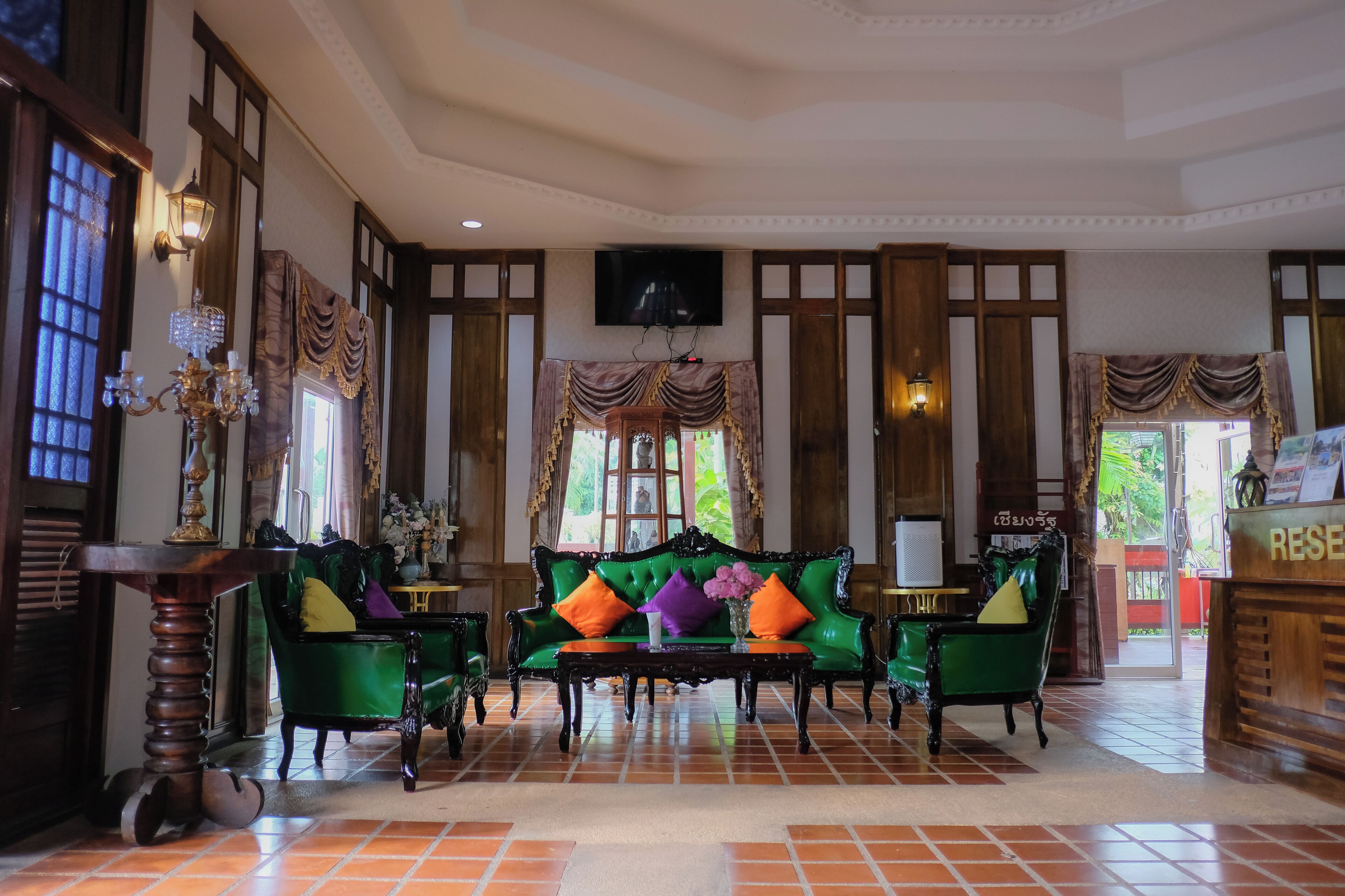 A lobby with a green sofa, a wooden reception desk, and a tiled floor.