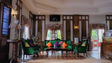 A lobby with a green sofa, a wooden reception desk, and a tiled floor.