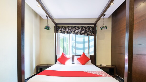 A hotel room with a large bed, two nightstands, a telephone, and a window with striped curtains. - OYO 852 Kings 10 (Bengaluru)