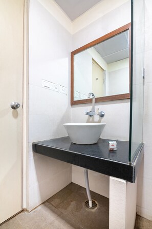 A bathroom with a white sink, black countertop, and a mirror with a wooden frame.