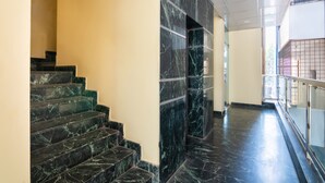 A modern interior with marble stairs and a glass railing. - OYO 852 Kings 10 (Bengaluru)