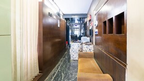 A narrow hallway with wooden paneling, a marble floor, and a bench. - OYO 852 Kings 10 (Bengaluru)