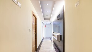 A hotel corridor with a marble floor, wooden doors, and a modern ceiling with recessed lighting. - OYO 852 Kings 10 (Bengaluru)