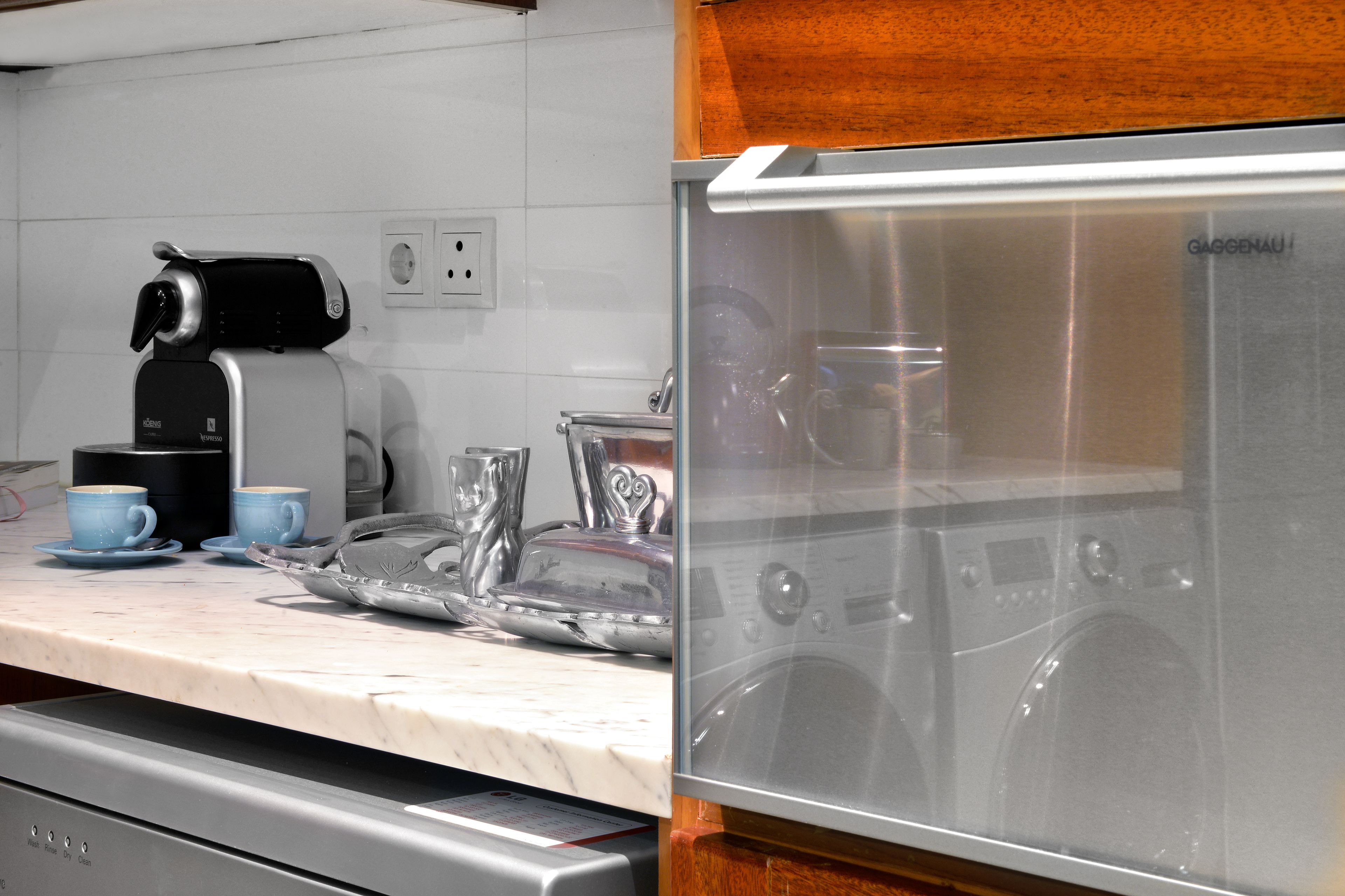 A kitchen with a coffee maker, two cups, a toaster, and a dishwasher.