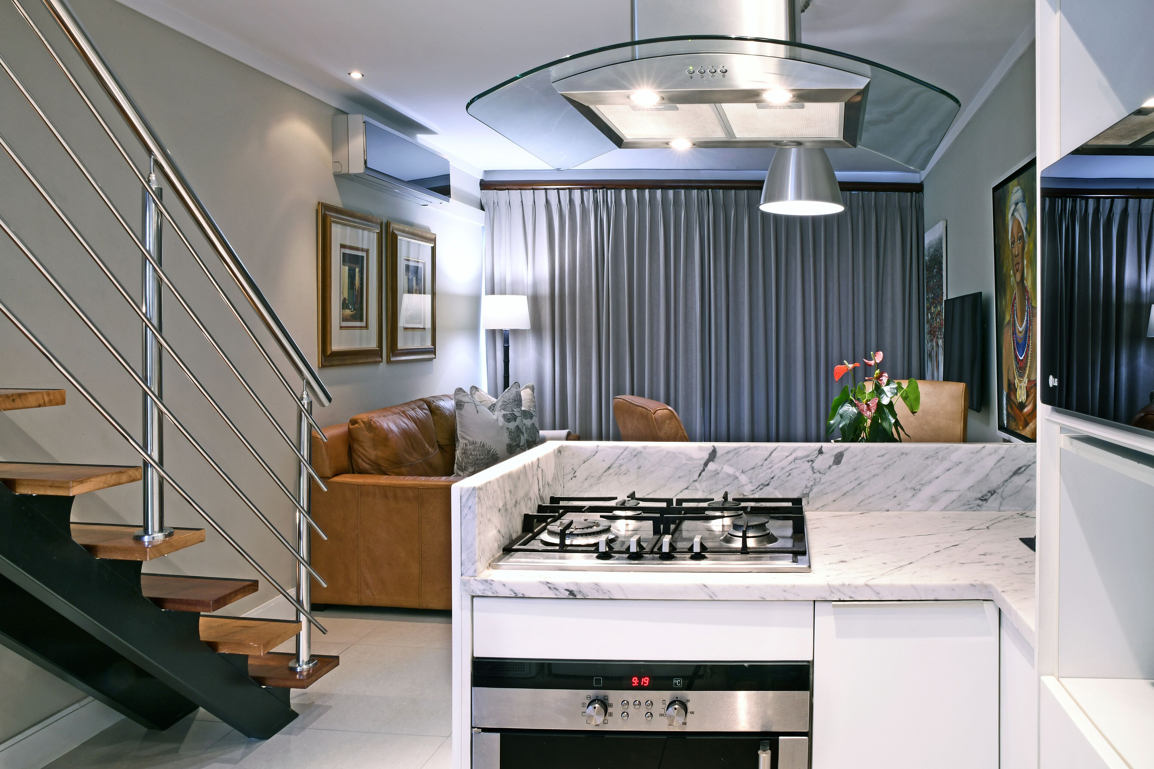 A modern kitchen with a gas stove, marble countertop, and a stainless steel range hood.