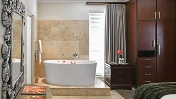 A modern bathroom with a freestanding bathtub, a large mirror, and a wooden wardrobe.