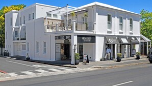A white building with multiple storefronts, including a jewelry store and a classic car dealership. - Le Petit Bijou Boutique Aparthotel (Franschhoek)