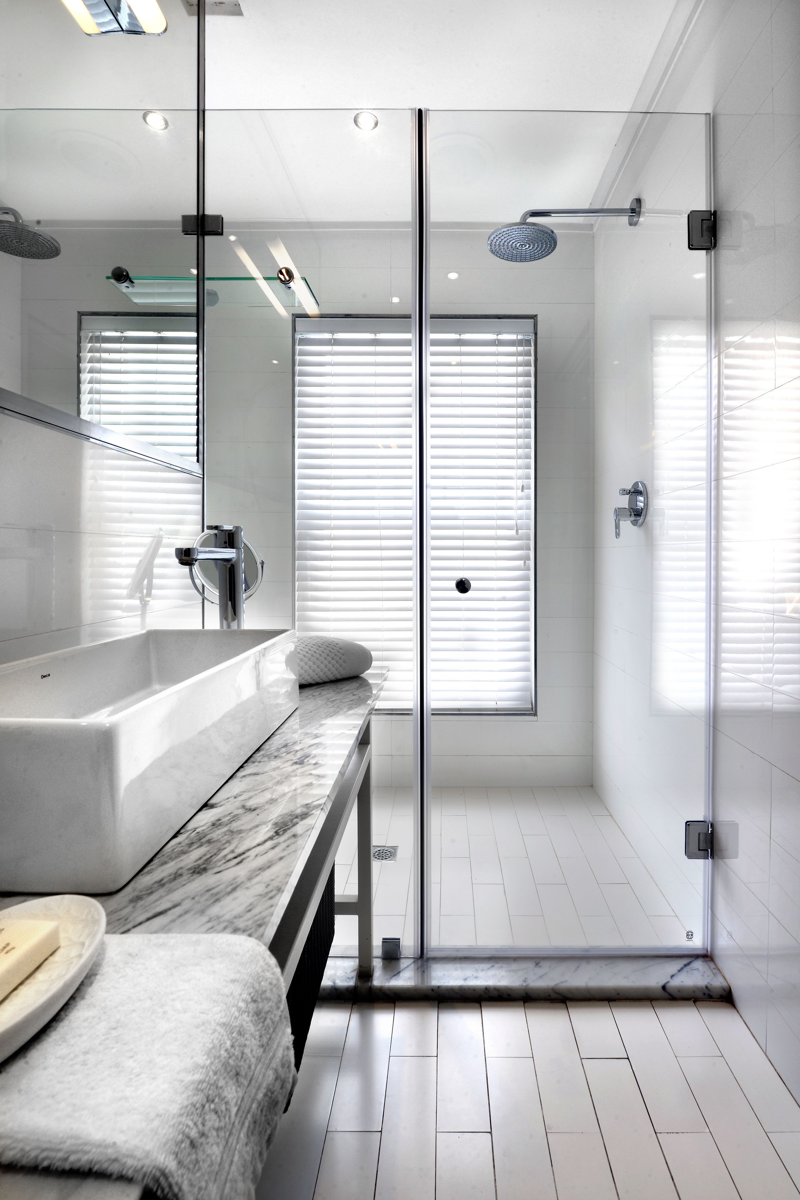 A modern bathroom with a glass-enclosed shower, a large bathtub, and a vanity with a marble countertop.