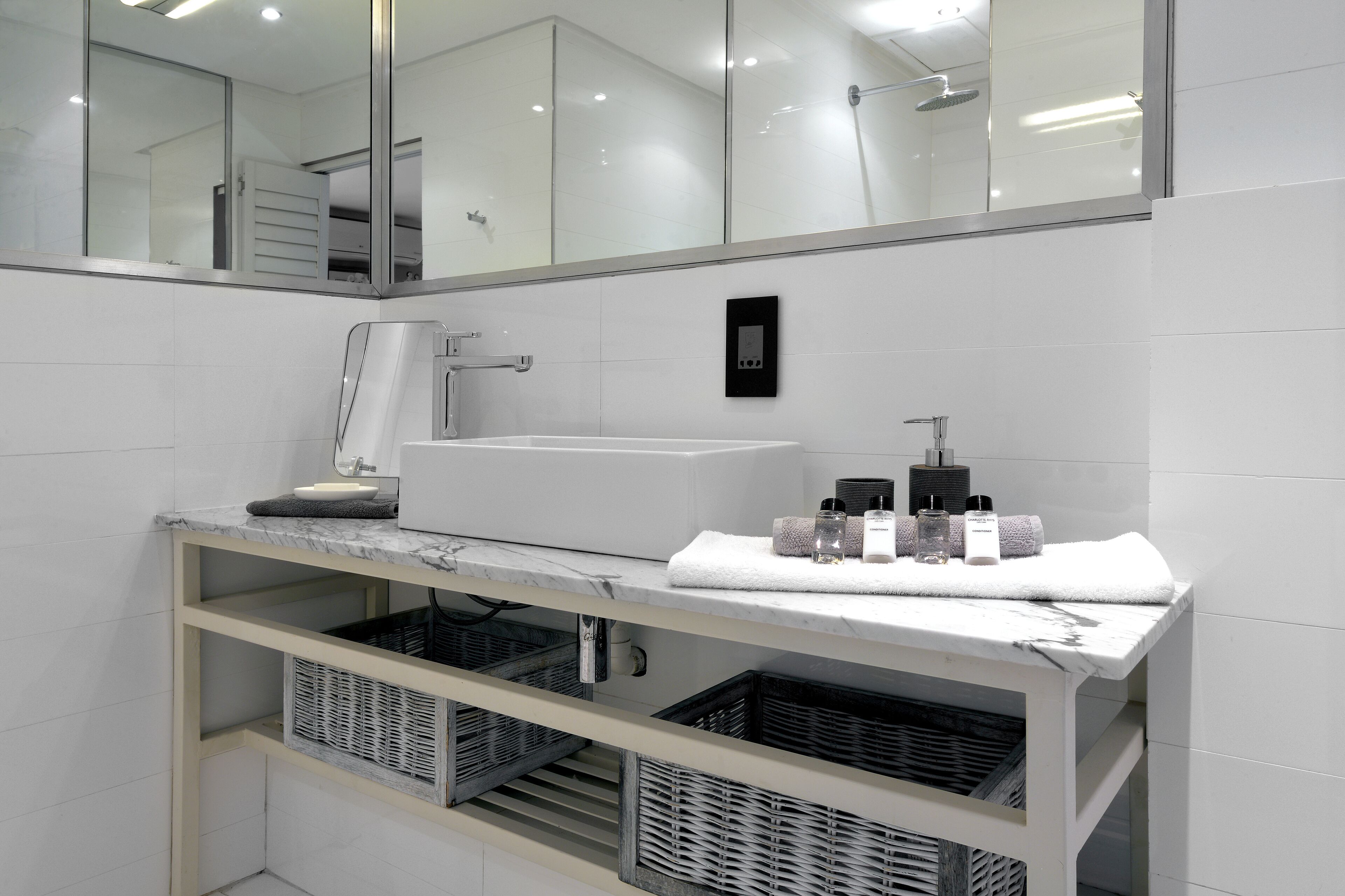 A modern bathroom with a white sink, a mirror, and a marble countertop.