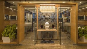 A reception area with a wooden reception desk, a Buddha statue, and a patterned wall. - GCC Northside Hotel (Mumbai)