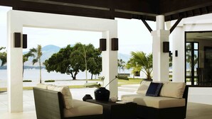 A modern outdoor seating area with wicker furniture and a view of the sea and mountains. - Hotel Kamana Sanctuary Resort and Spa (Morong)