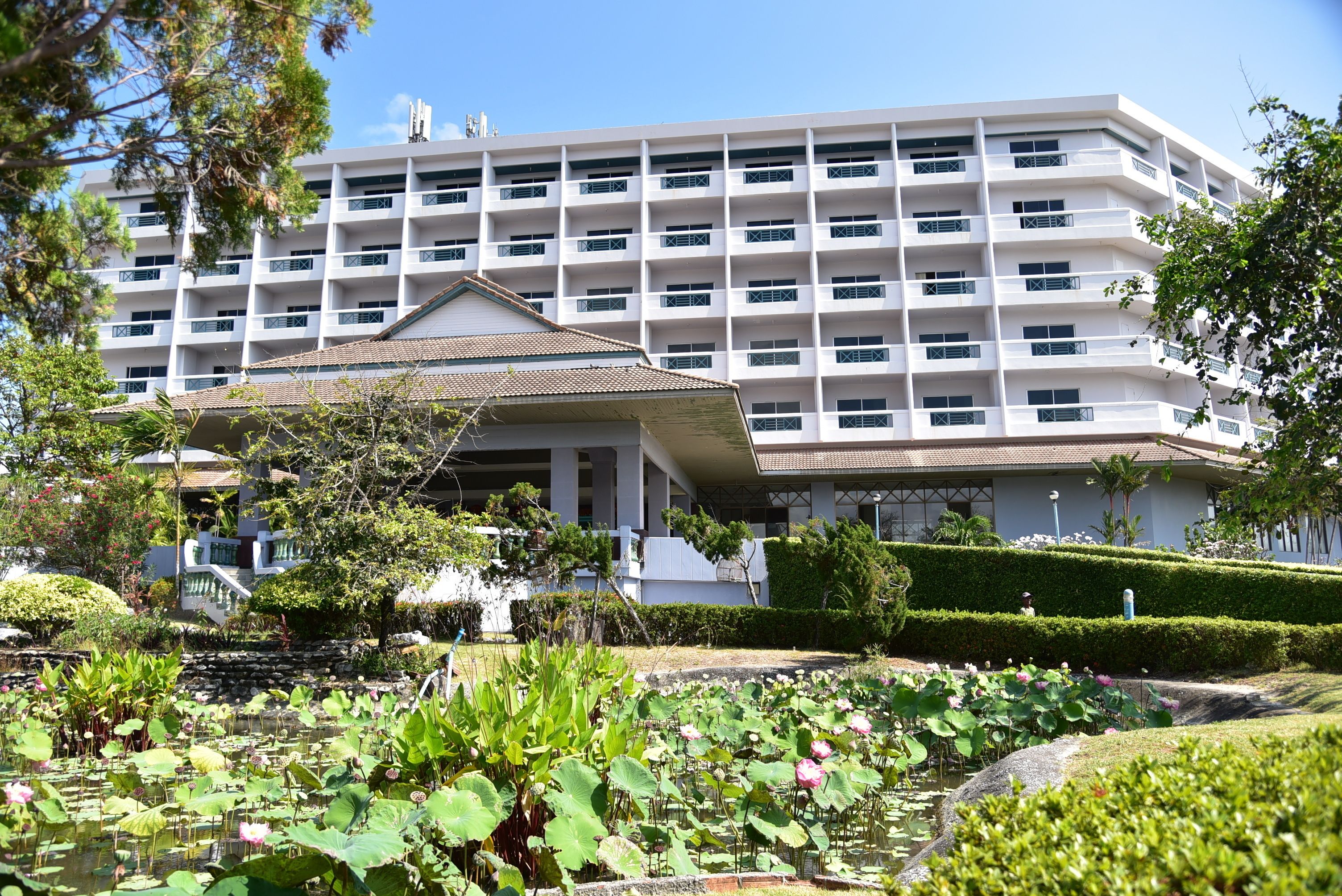Un hotel de varios pisos con un patio central que incluye un estanque con plantas de loto.