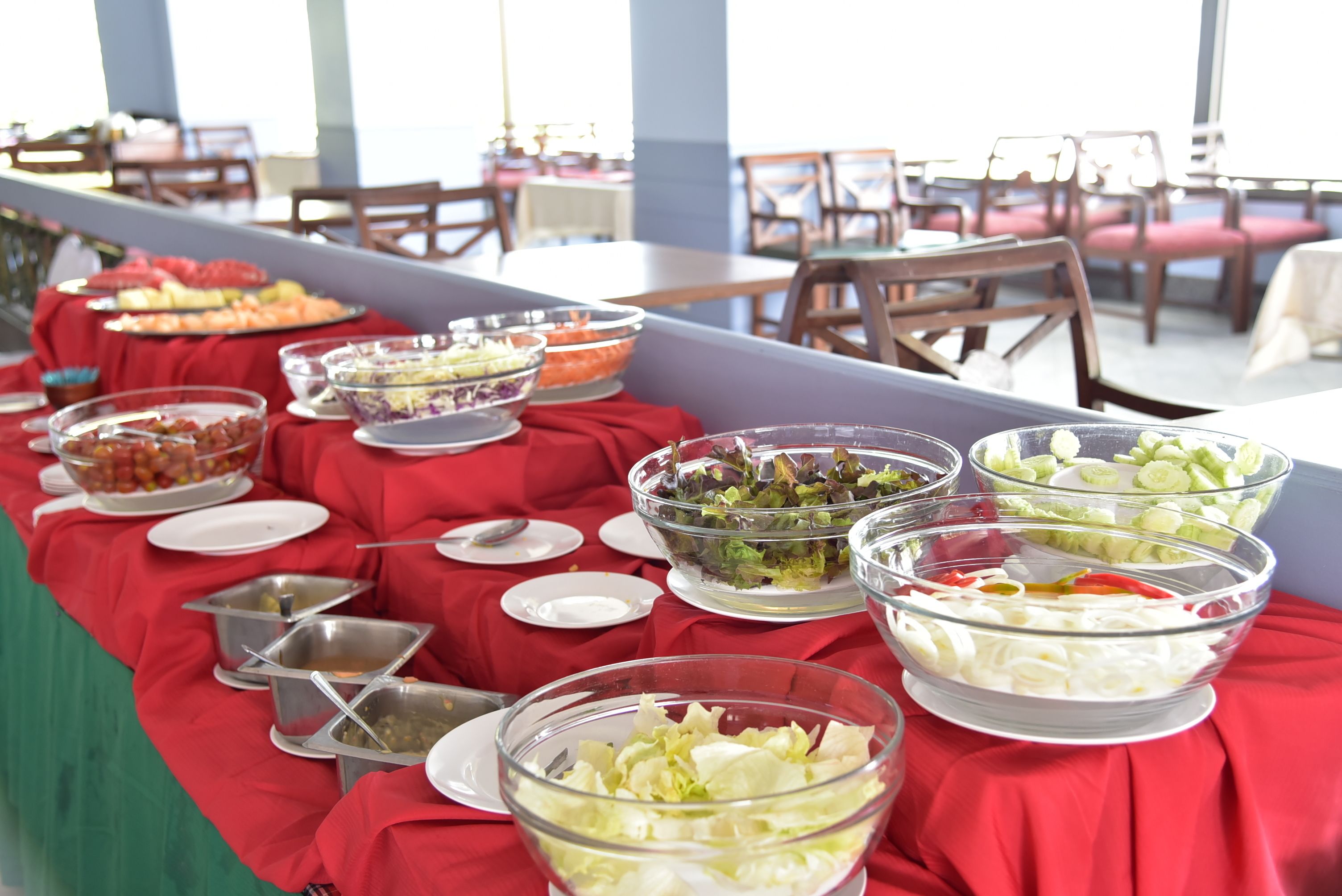 A buffet table with various food items and clear glass bowls.