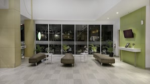 Un vestíbulo moderno con mostrador de recepción, zona de estar y ventanas amplias.