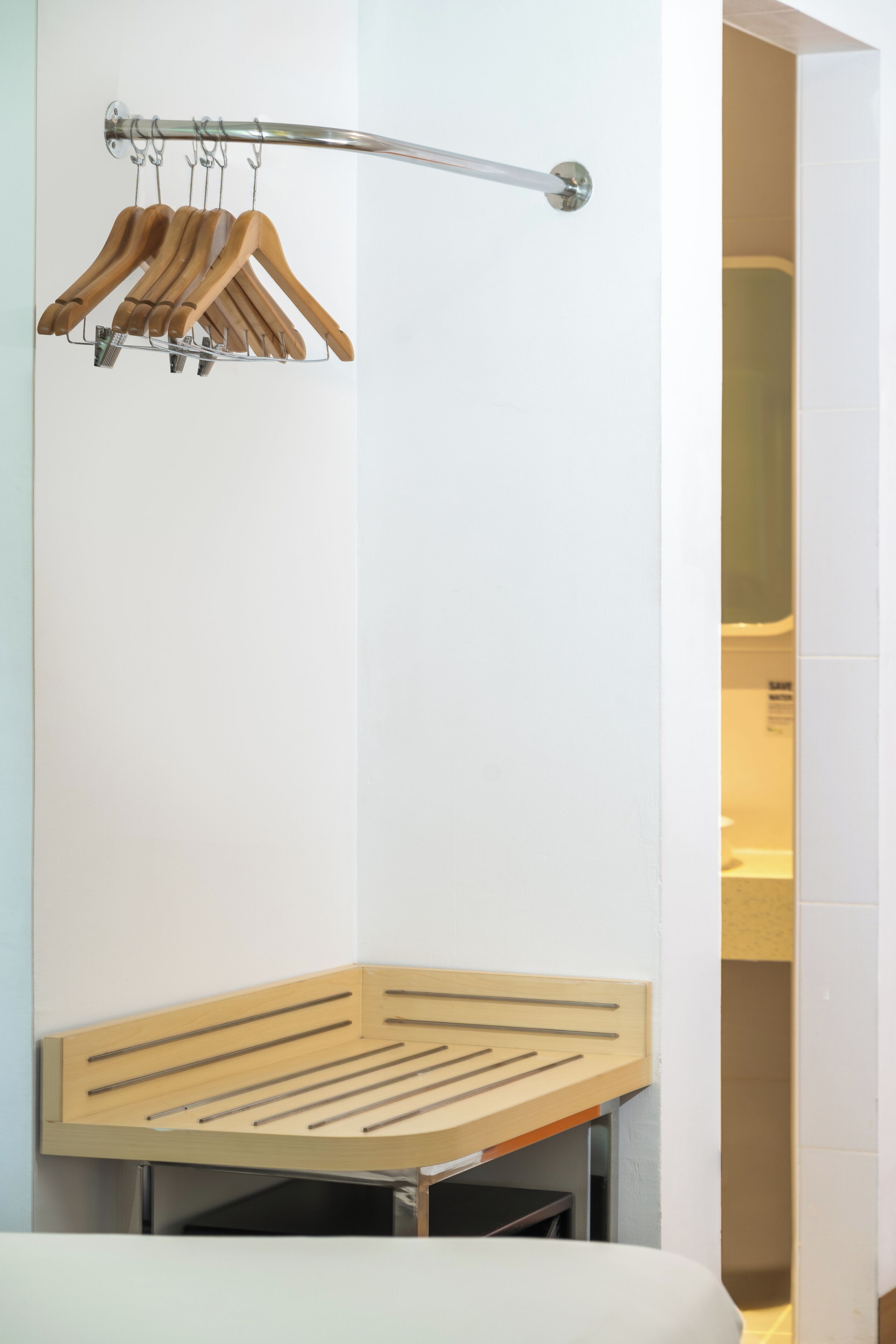 A modern bathroom with a wooden towel rack, a towel rack with wooden hangers, and a wooden towel rack with metal hooks.