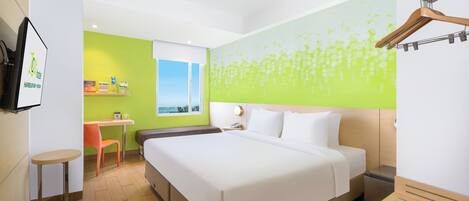 A hotel room with a large bed, a desk, a chair, a small table, and a view of the outdoors.