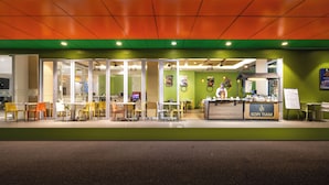 Un espacio interior bien iluminado con una paleta de colores verde y naranja, que presenta un mostrador con el nombre
