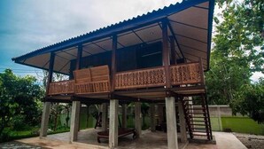 A two-story house with a balcony, wooden railings, and a concrete foundation. - Little Teak Home Stay (San Sai)