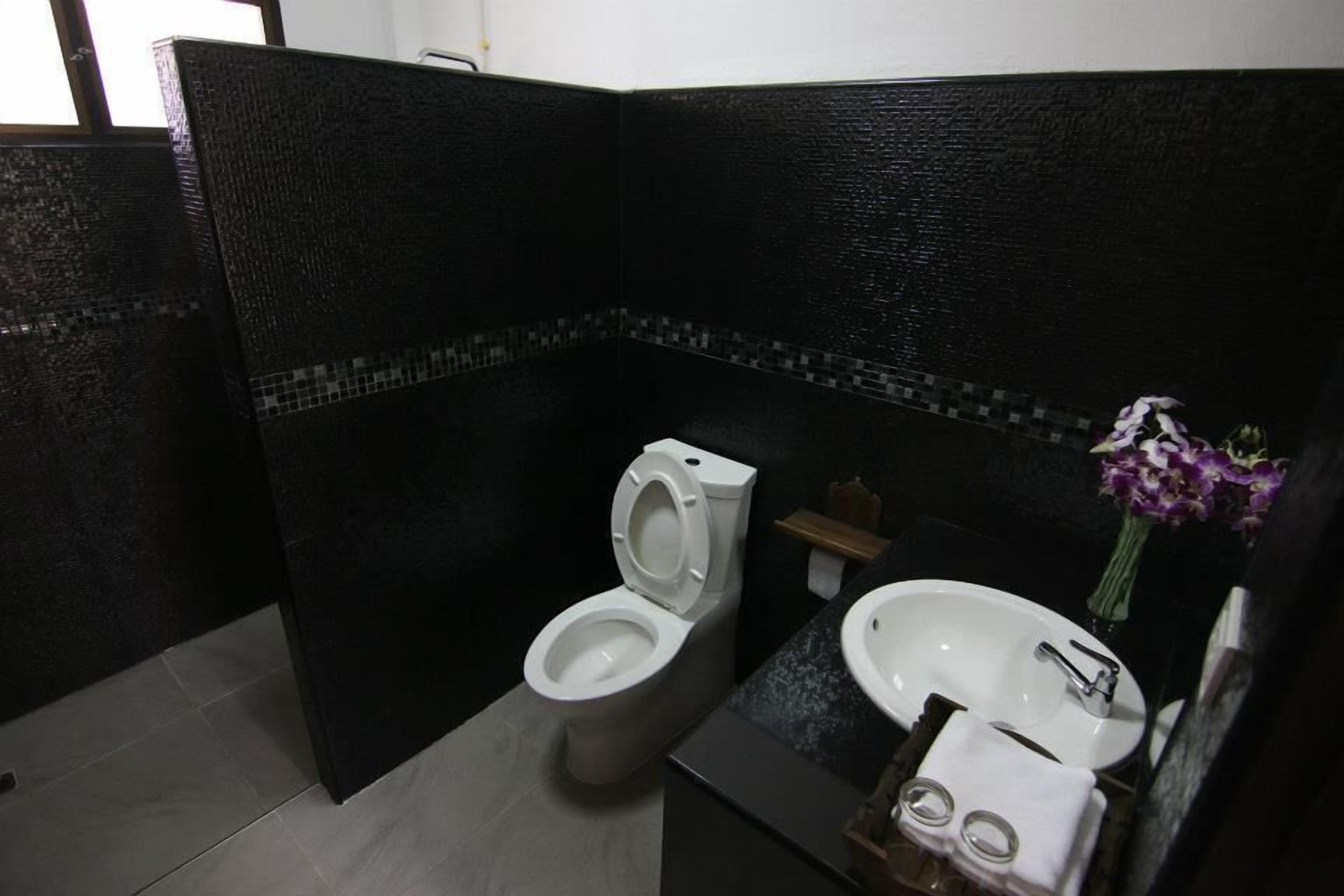 A modern bathroom with a toilet, sink, and a small shelf.