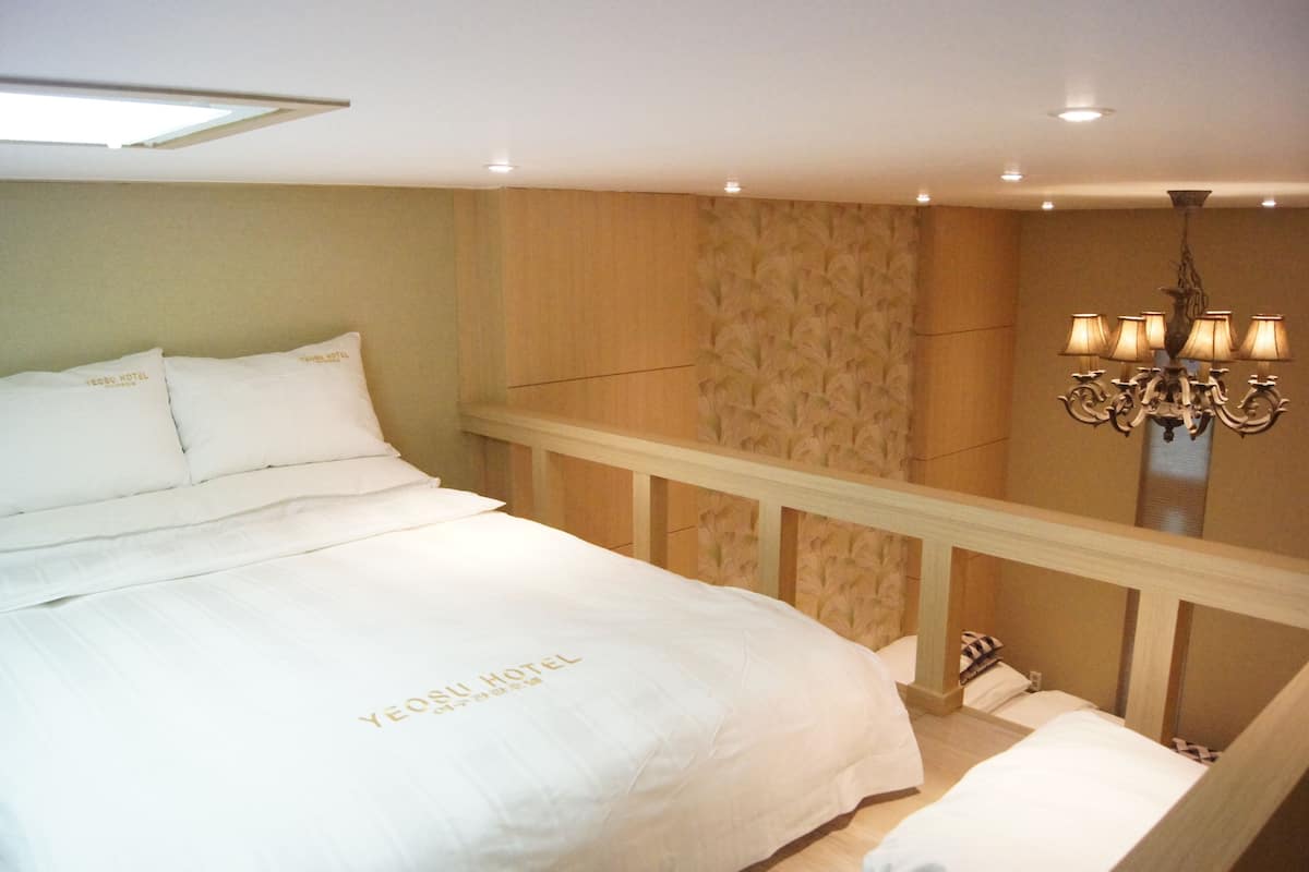 Une chambre d’hôtel avec un grand lit, un lustre et une tête de lit en bois.